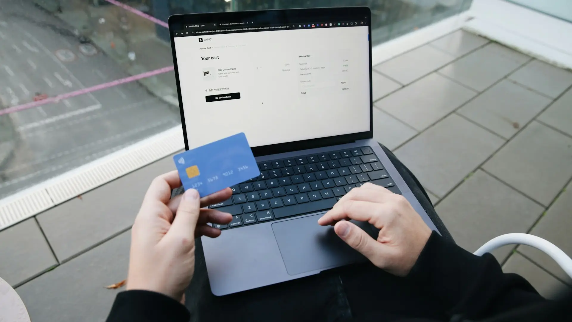 Personne avec PC portable sur les genoux et carte bancaire en main